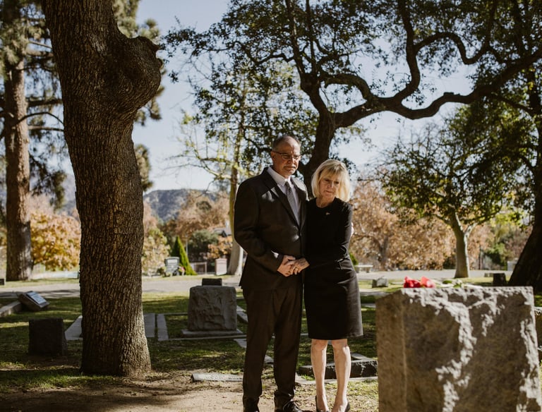 A couple in black in front of a grave