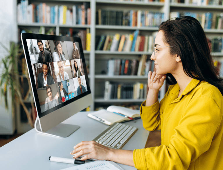 a woman sitting at a computer screen with a computer screen showing a video chat