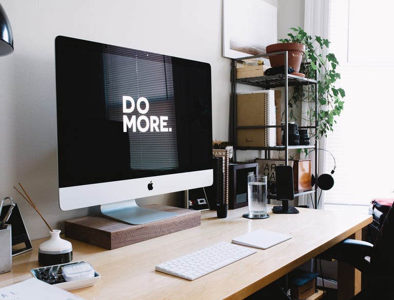 Organized desk and computer monitor with "do more." displayed on the screen