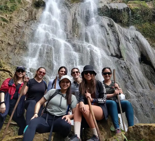 a group of people standing around a waterfall