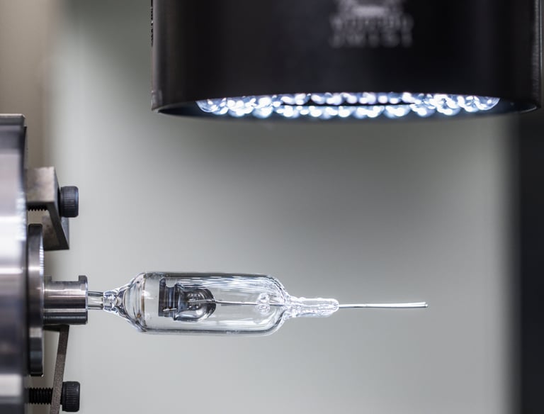 Precision manufacturing of a miniature glass halogen light bulb using automated CNC industrial equipment.