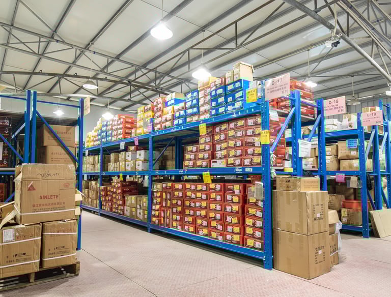 Wide view of inventory boxes stacked on blue industrial metal shelving inside a warehouse facility.