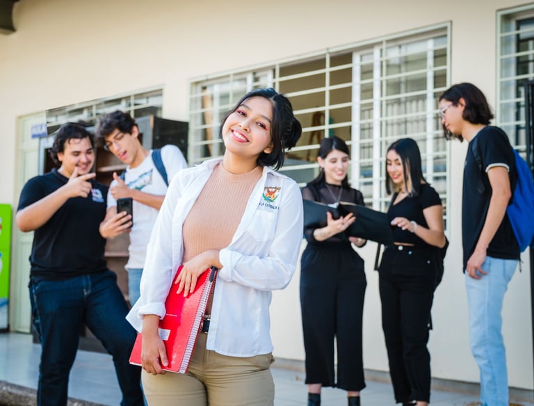 una estudiante sonriendo y detras hombres y mujeres estudiantes