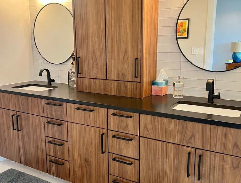 Modern bathroom double vanity with walnut wood cabinets, black hardware, and round mirrors.