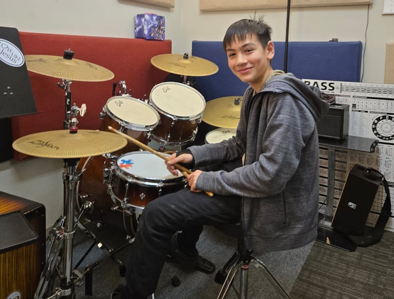 Teenager learning to play the drum set.