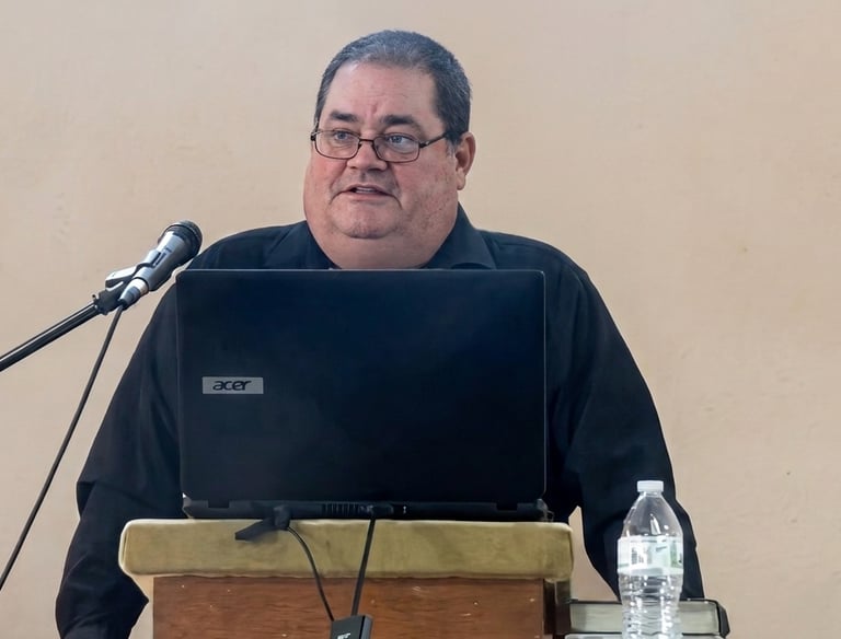 Pastor giving a sermon with an Acer laptop and microphone at a podium.
