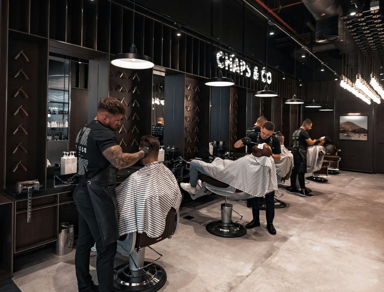 Barberos profesionales cortando el cabello y afeitando a clientes.