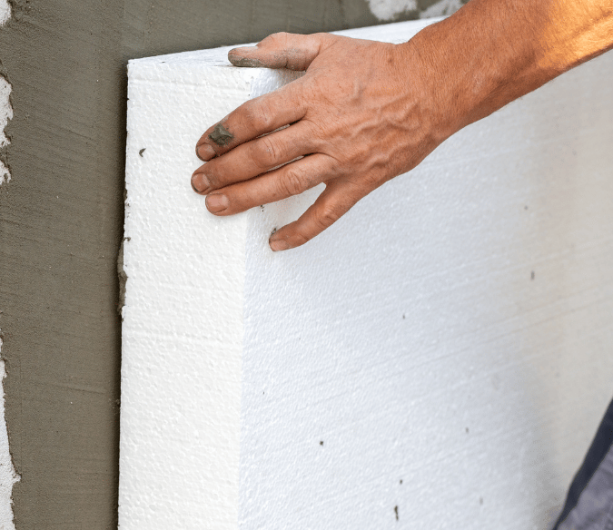 homem colando placa de isopor na parede para fazer isolamento térmico