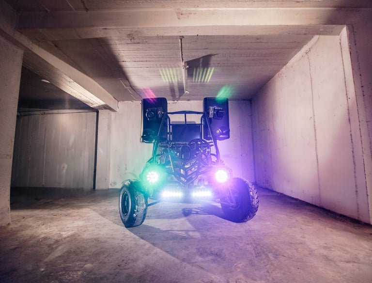 Custom off-road dune DJ buggy with LED lights and a loud audio speaker system in a concrete garage.