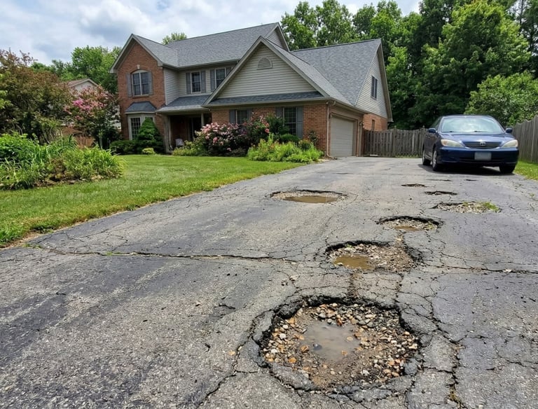 Driveway in North Olmstead with several potholes.