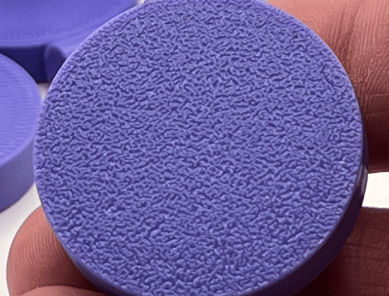 Close-up of a purple 3D printed frag plate showing a textured fuzzy skin surface finish.