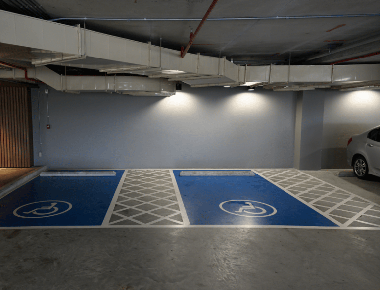 Plazas de minusválido de aparcamiento subterráneo, pintadas de color azul con líneas blancas