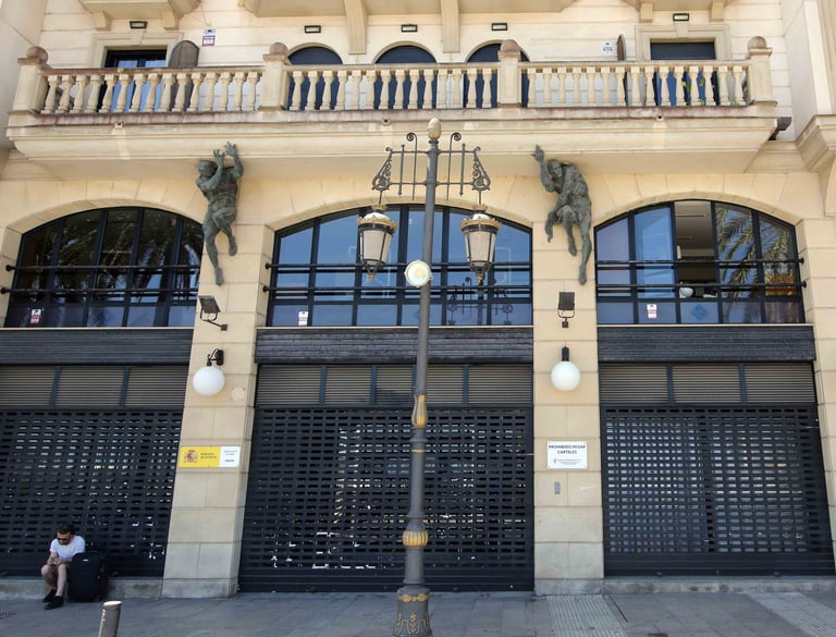 Ornate street lamp in front of a historic building with architectural statues and closed security shutters.