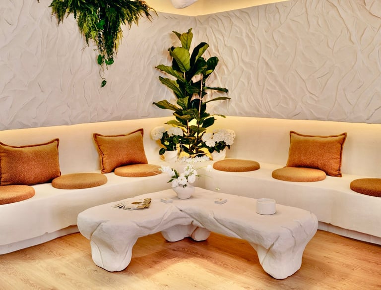 Modern lounge area featuring white tufted club chairs, a blue sofa, and red walls.
