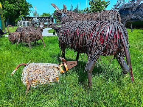 Handcrafted metal animal sculptures made from recycled scrap iron and wire displayed on a green lawn.