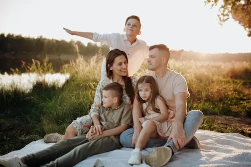 large young Caucasian family smiling at a sunset picnic