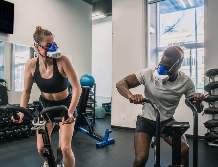 a man and woman in masks in a gym taking a VO2MAX test