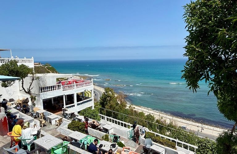 Outdoor terrace restaurant overlooking the Mediterranean Sea and coastline in Tangier, Morocco.