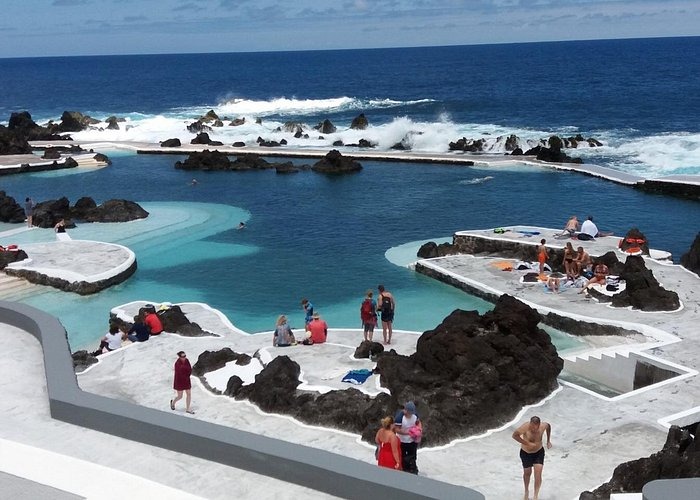 Tourists relaxing at Porto Moniz natural volcanic swimming pools in Madeira, Portugal.