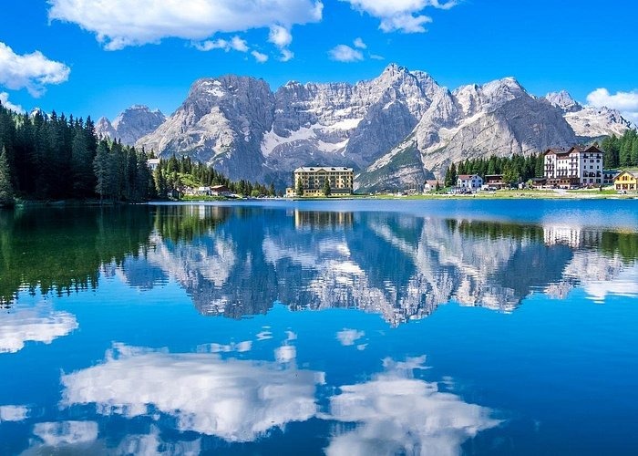 Scenic view of Misurina Lake in the Italian Dolomites with mountain reflection and luxury hotels.