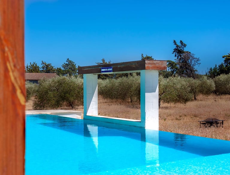 Swimming pool with beach chairs, wide view and waterfall, built-in cascade at Domaine Des Lucques