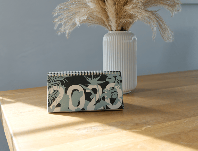 Ein Tischkalender für das Jahr 2020 mit botanischen Motiven auf einem Holztisch.