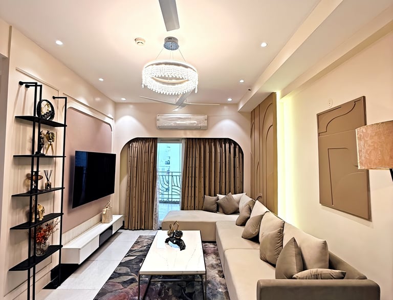Modern living room featuring a beige sectional sofa, floral area rug, and elegant crystal chandelier.