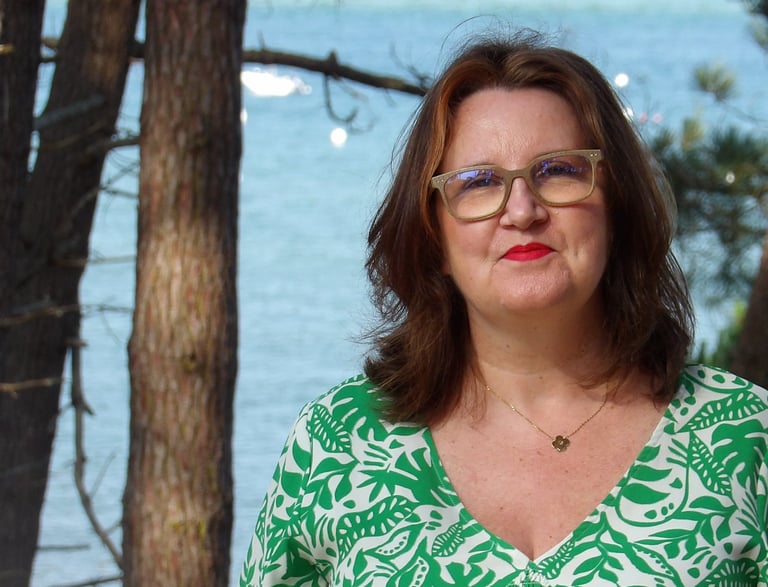 Portrait de la sophrologue en extérieur, devant un paysage de mer et de pins, illustrant le contact.