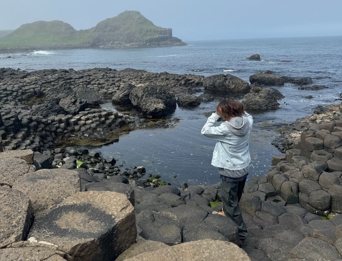 a person standing on a rock formation in the ocean, Ireland, Giant Causeway