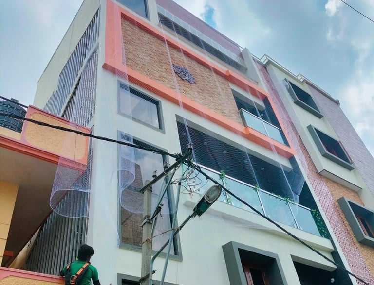 A technician installing pigeon nets on a rooftop in Chennai under a clear blue sky.