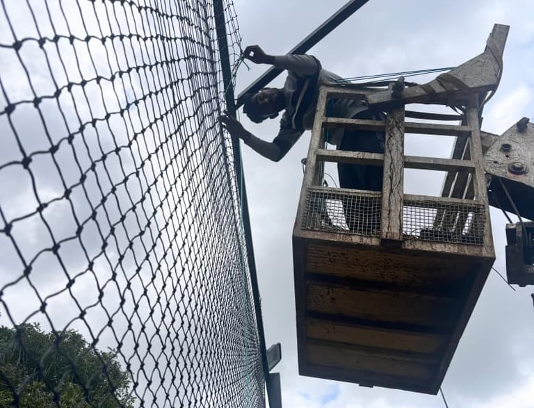 A technician carefully installing a sturdy sports net on a sunny Chennai sports field.