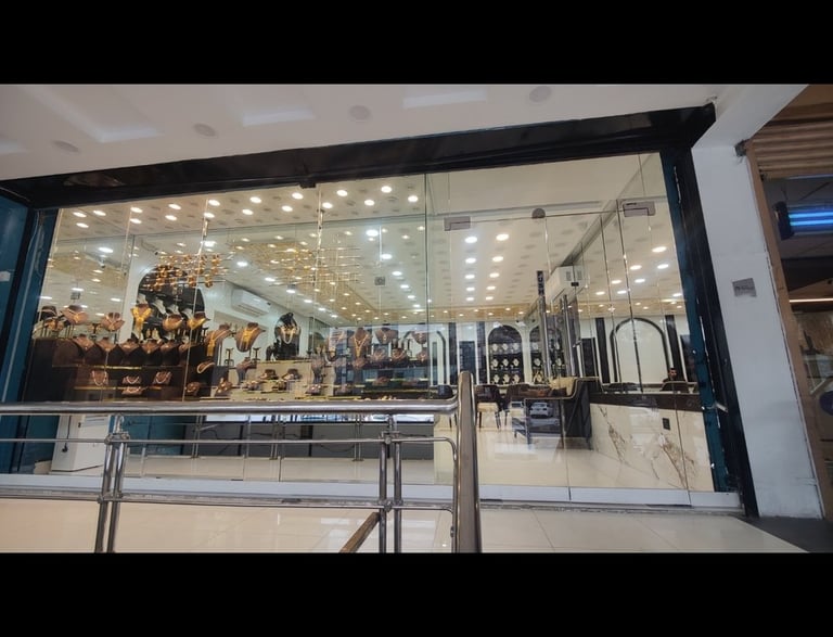 A luxury jewelry store storefront featuring elegant gold necklaces and diamond jewelry on display behind glass.