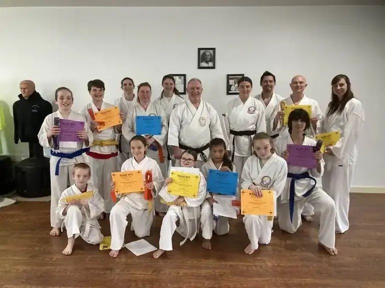 Students earning new belts pose on promotion day