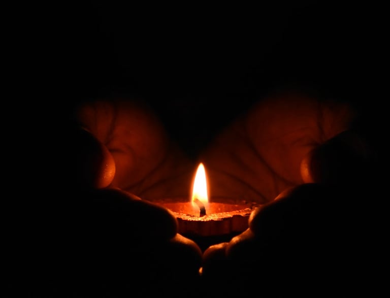 Hands protecting a small burning candle, symbolizing guidance and hope.