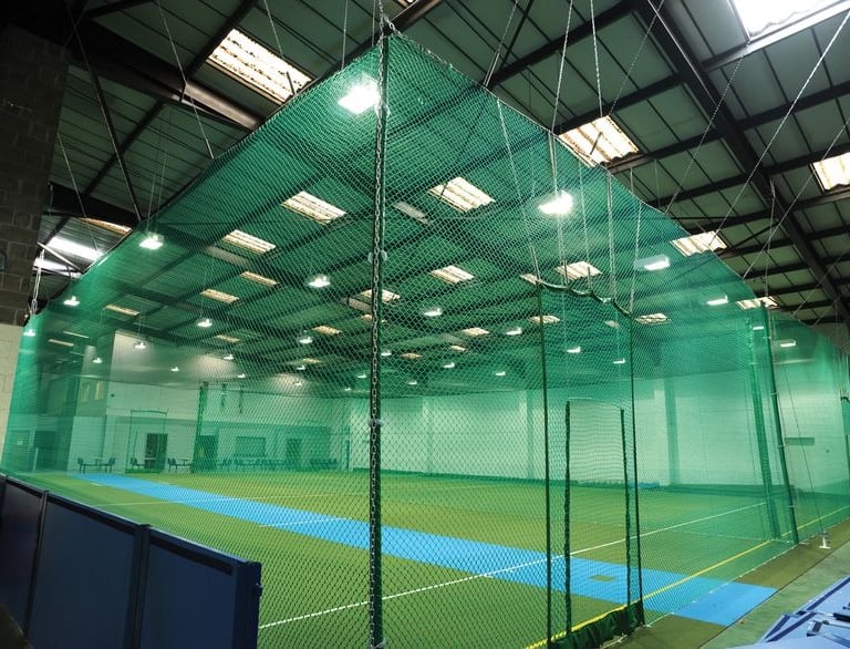 A close-up of a securely installed cricket net against a clear Bengaluru sky.