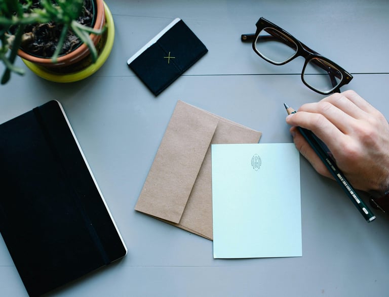 A person's hand holding a pen and writing on a notepad