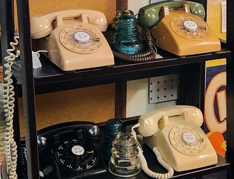 a shelf with a bunch of old fashioned telephone phones