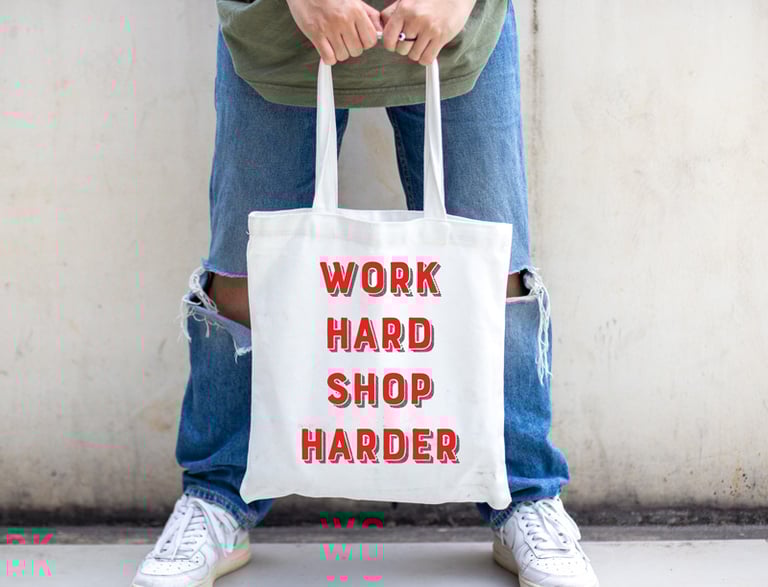 a person holding one of work hard shop harder tote bags.