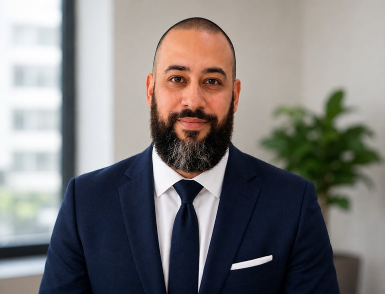 Professional headshot of a bearded man in a navy blue suit and tie for business profile.