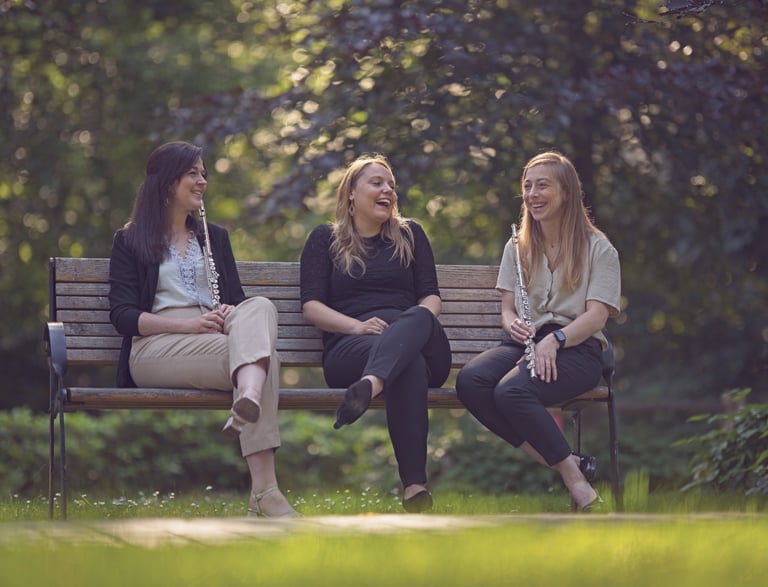 three women sitting on a bench in a park