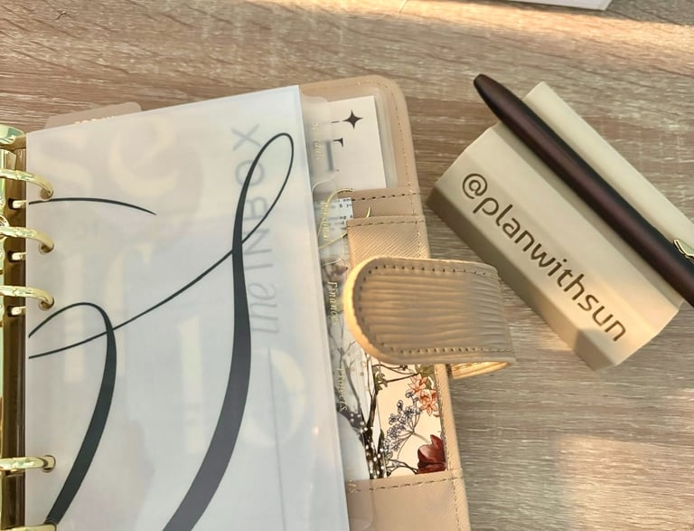 Aesthetic beige ring planner with vellum dividers and a pen rest on a wooden desk.
