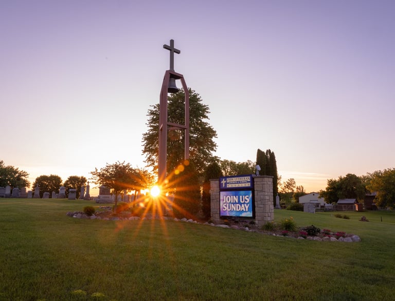 a church sign with a cross on the grass