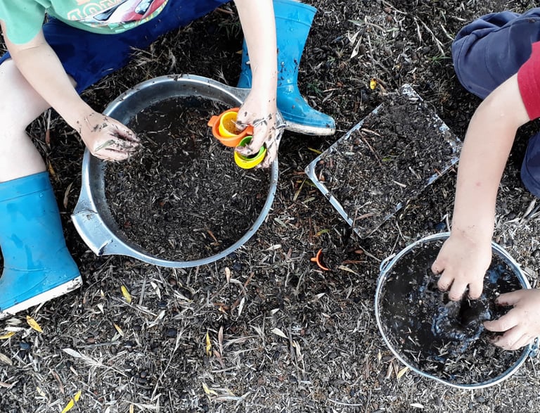two boys playing with dirt in a garden