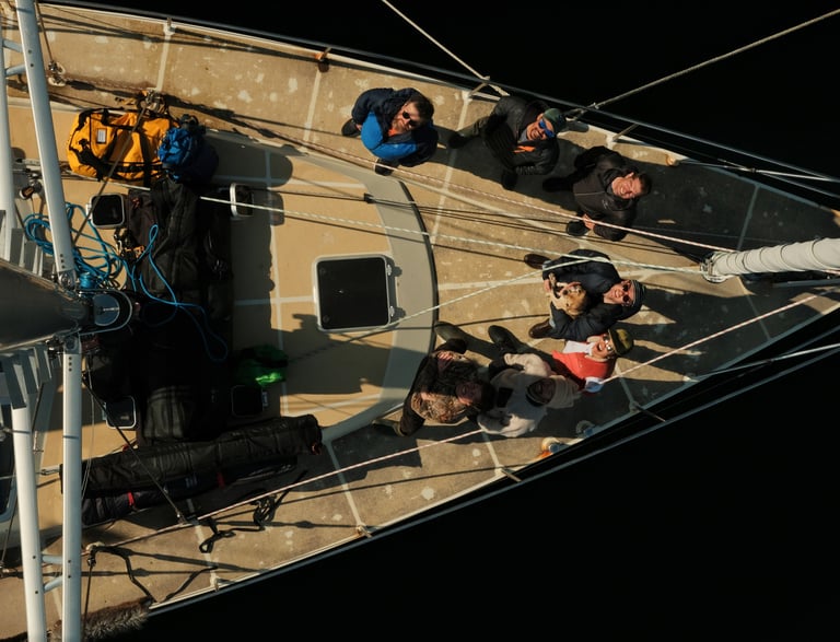 A group of people standing on a sailing boat in the lyngen alps looking to t he sky