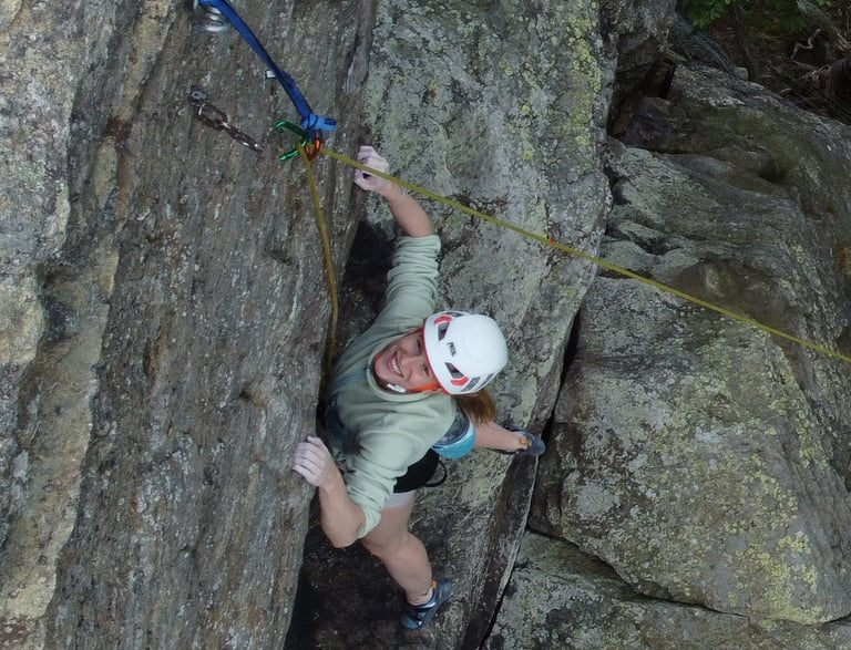 Kletterkursteilnehmerin ist glücklich über geschaffte Route bei einem Outdoor - Kletterkurs.