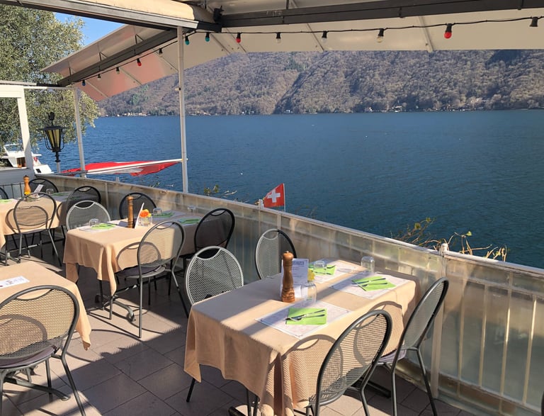 Una terrazza sul lago di Lugano del ristorante Roccabella con tavoli e sedie