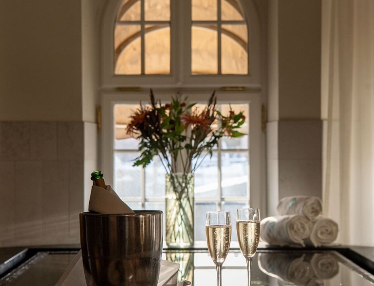 Luxury spa experience with champagne, macarons, and flowers by an indoor pool.