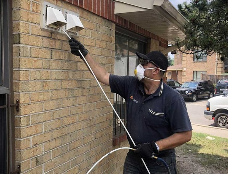a man in a mask and gloves is cleaning dryer vent