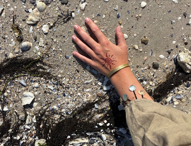 a person's hand with a wrist tattoo on it on earth with shells tribal pattern art handmade