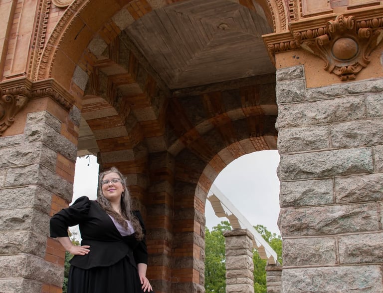 A businesswoman standing in the opening of a stone gazebo-like structure